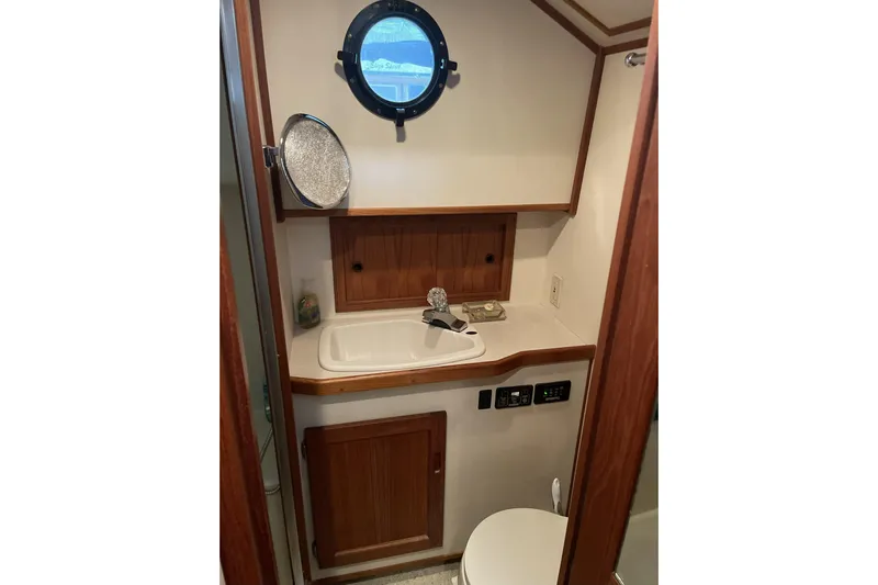 Lagnaf Yacht Photos Pics 2002 Nordic Tug 37 bathroom with wooden cabinetry and porthole window.