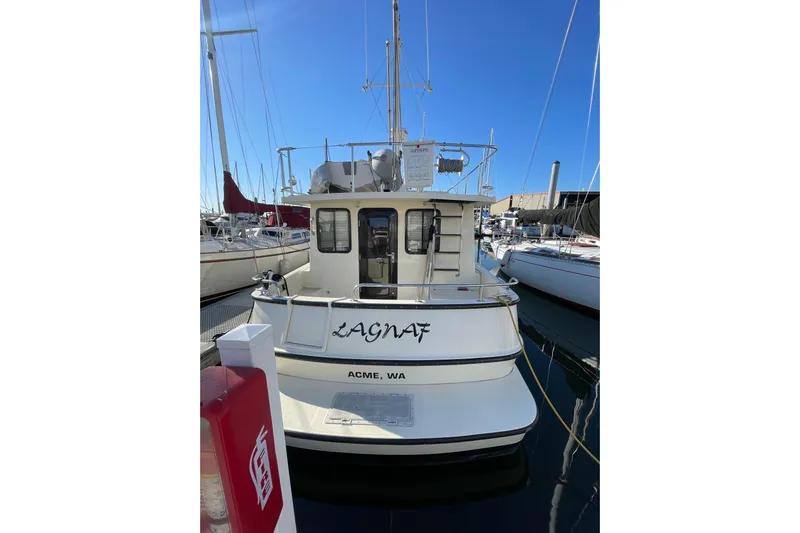 Lagnaf Yacht Photos Pics 2002 Nordic Tug 37 docked at marina, rear view with clear blue sky.
