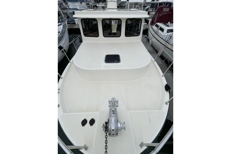 Lagnaf Yacht Photos Pics 2002 Nordic Tug 37 boat deck with anchor and railing in marina setting.