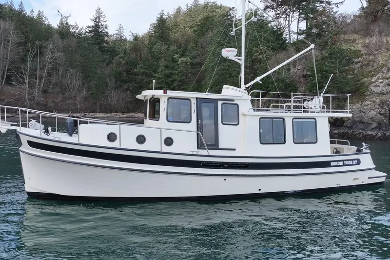 Lagnaf Yacht Photos Pics 2002 Nordic Tug 37 boat on calm water near a forested shoreline.