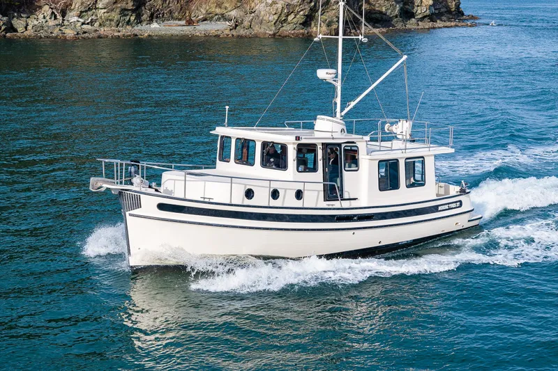 Lagnaf Yacht Photos Pics 2002 Nordic Tug 37 cruising on blue water near rocky shoreline.