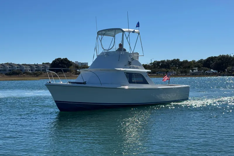 Bandit Yacht Photos Pics 1970 Bertram 31 Flybridge Cruiser on calm water, American flag displayed.