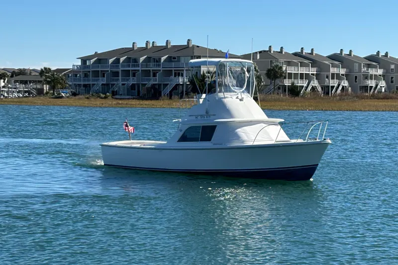 Bandit Yacht Photos Pics 1970 Bertram 31 Flybridge Cruiser on water near waterfront homes.