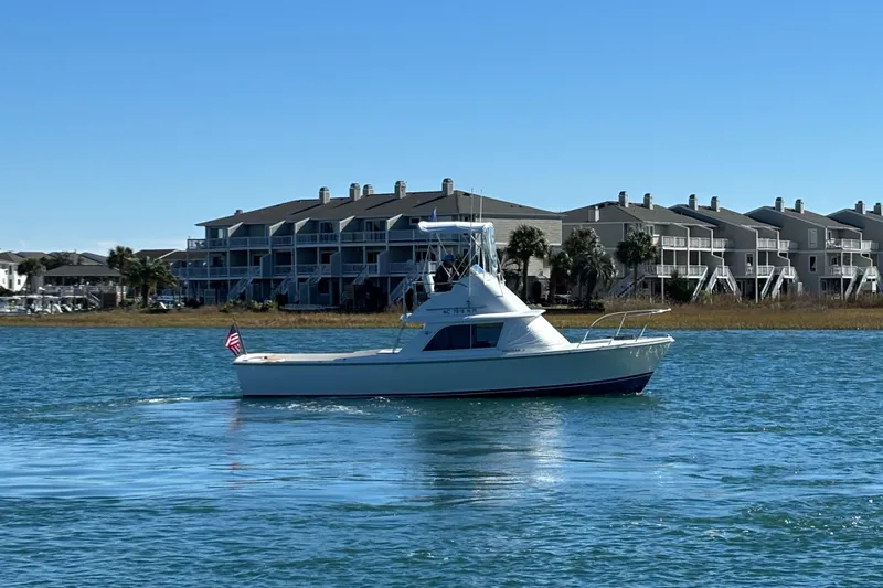Bandit Yacht Photos Pics 1970 Bertram 31 Flybridge Cruiser on water near waterfront homes.