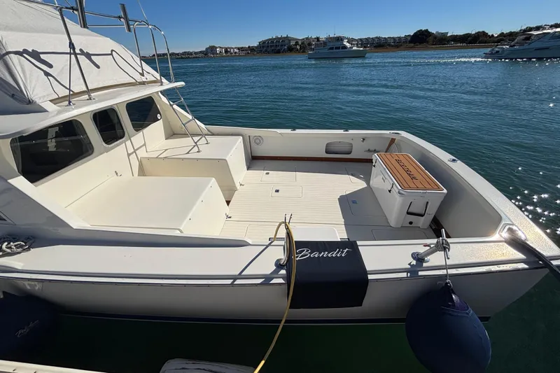 Bandit Yacht Photos Pics 1970 Bertram 31 Flybridge Cruiser docked, featuring spacious deck and scenic waterfront view.