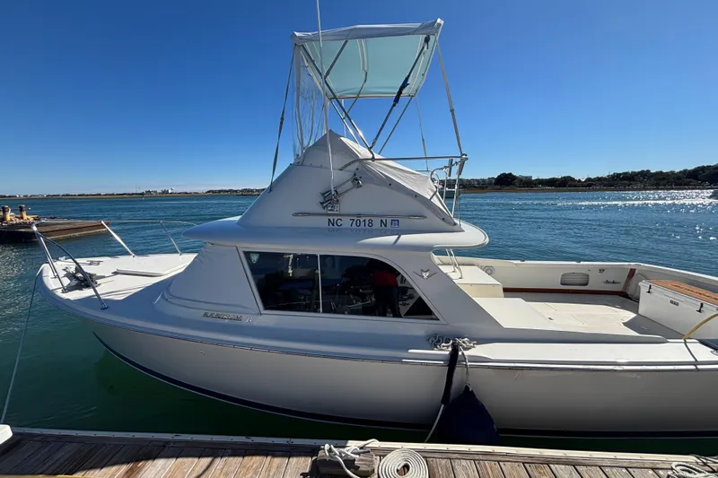 Bandit Yacht Photos Pics 1970 Bertram 31 Flybridge Cruiser docked by the water on a sunny day.