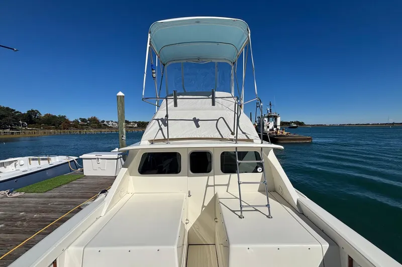 Bandit Yacht Photos Pics 1970 Bertram 31 Flybridge Cruiser docked by the water on a clear day.