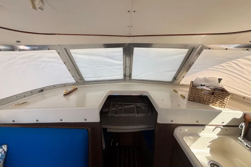 Bandit Yacht Photos Pics 1970 Bertram 31 Flybridge Cruiser interior with helm, windows, and wicker basket.