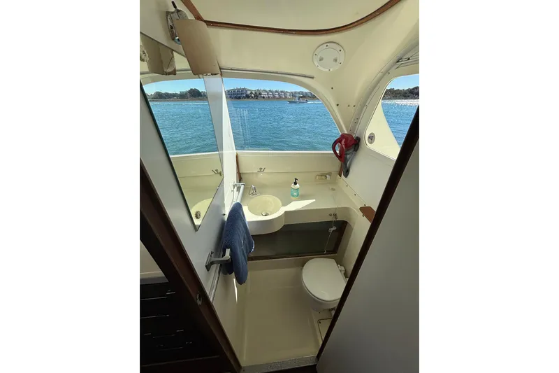 Bandit Yacht Photos Pics 1970 Bertram 31 Flybridge Cruiser bathroom with ocean view, featuring sink and toilet.