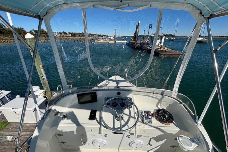 Bandit Yacht Photos Pics 1970 Bertram 31 Flybridge Cruiser helm with marina view, clear skies, and calm waters.