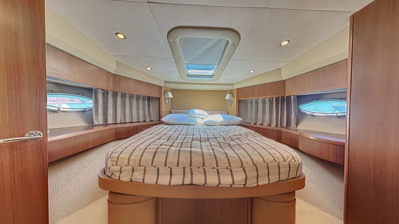  Yacht Photos Pics Luxurious cabin interior of 2010 Princess 62 yacht with cozy bed and elegant wood finish.