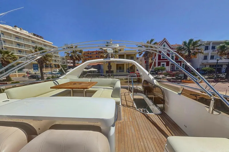  Yacht Photos Pics Luxurious 2010 Princess 62 yacht deck with seating and table, docked near palm trees and buildings.