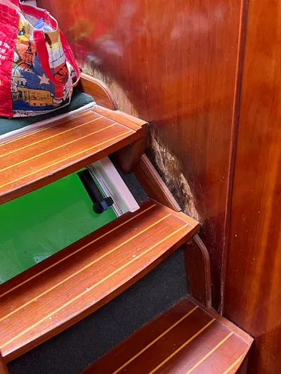 Taco Truck Yacht Photos Pics Wooden stairs inside a 1996 Prout 45 boat, with a colorful bag on top.