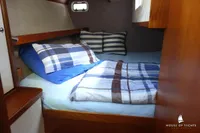 Cozy cabin interior of 2014 Von Ahlen 403 yacht with plaid bedding and striped pillows.