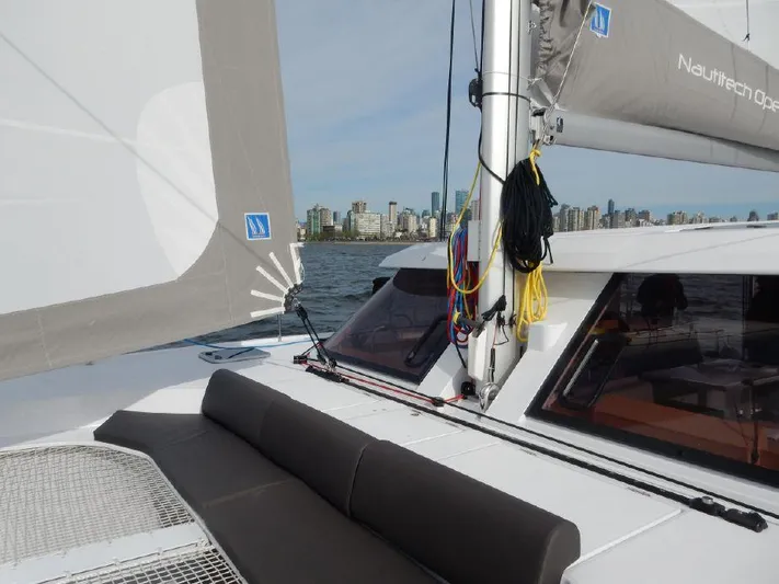 Escape Yacht Photos Pics Nautitech 40 Open 2016 catamaran sailing near city skyline, featuring deck and seating area.