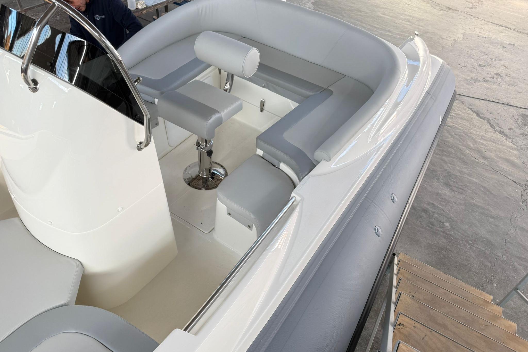 Modern boat interior with gray seating and sleek design, featuring a steering console.