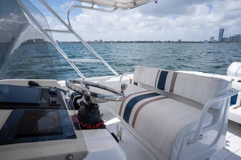  Yacht Photos Pics 1999 Intrepid 35 boat interior with striped seating and steering wheel, overlooking ocean and cityscape.