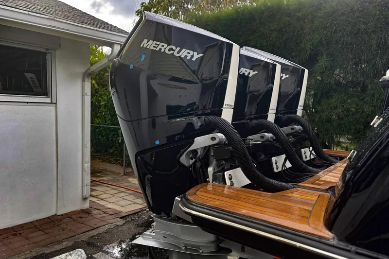  Yacht Photos Pics Triple Mercury outboard engines on a 2014 Scout 350 LXF boat, parked near a house.