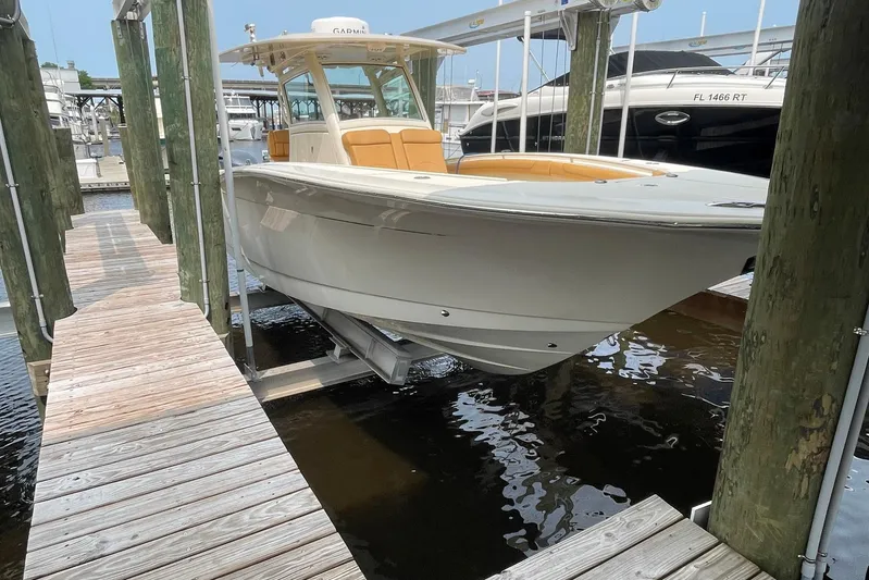  Yacht Photos Pics 2015 Scout 300 LXF boat docked on a lift in a marina.