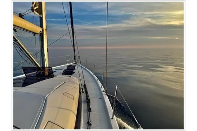  Yacht Photos Pics Sailing on a 2021 Jeanneau 60 yacht at sunset over calm waters.
