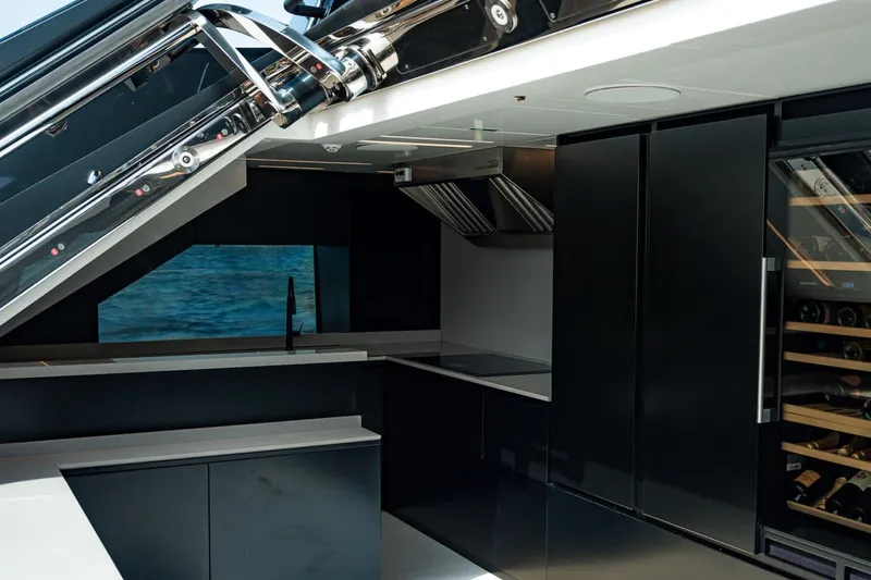  Yacht Photos Pics Luxurious modern kitchen interior on Maori 125 yacht, featuring sleek black cabinetry and wine storage.