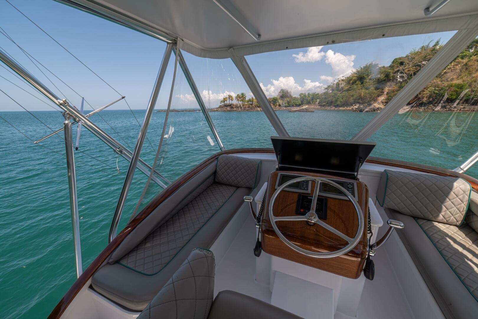 Helm of 1991 Gamefisherman 40 boat with ocean view and lush coastline.