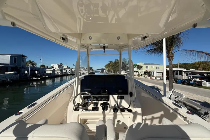  Yacht Photos Pics 2022 Cobia 320 Center Console boat interior with steering wheel and controls, docked by waterfront homes.