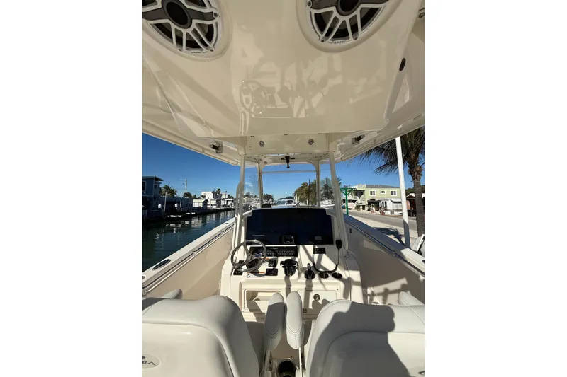  Yacht Photos Pics 2022 Cobia 320 Center Console boat interior with steering and controls, docked by waterfront homes.