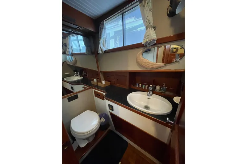 Amazing Grace Yacht Photos Pics 1983 Grand Banks 49 Classic yacht bathroom with sink, toilet, mirror, and wooden cabinetry.
