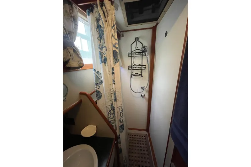 Amazing Grace Yacht Photos Pics Shower area in 1983 Grand Banks 49 Classic yacht with floral curtain and wall-mounted fixtures.