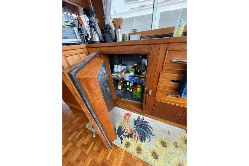 Amazing Grace Yacht Photos Pics Wooden kitchen interior of 1983 Grand Banks 49 Classic with open fridge and rooster-themed rug.