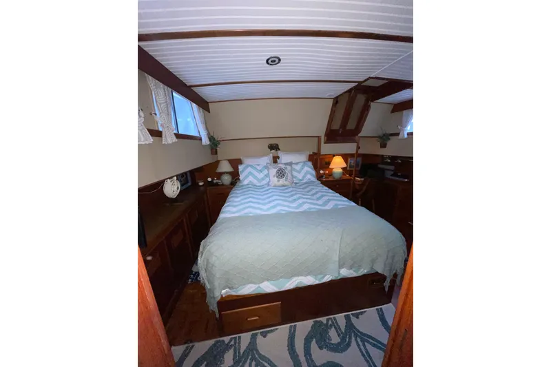 Amazing Grace Yacht Photos Pics Cozy bedroom interior of 1983 Grand Banks 49 Classic yacht with wood accents and soft lighting.