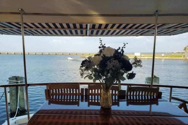  Yacht Photos Pics Aboard 1984 Hatteras 61 Cockpit MY, elegant dining area with floral centerpiece overlooking serene waters.