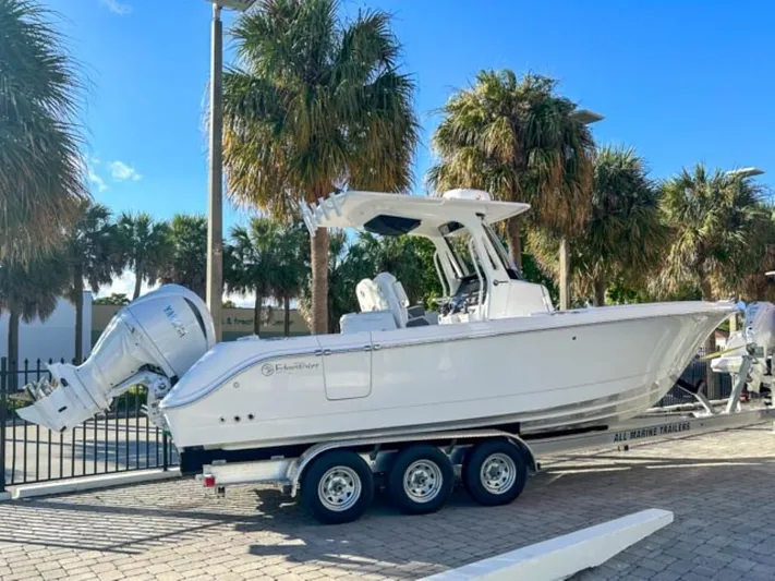  Yacht Photos Pics 2025 Edgewater 262CC boat on trailer, parked near palm trees under a clear blue sky.