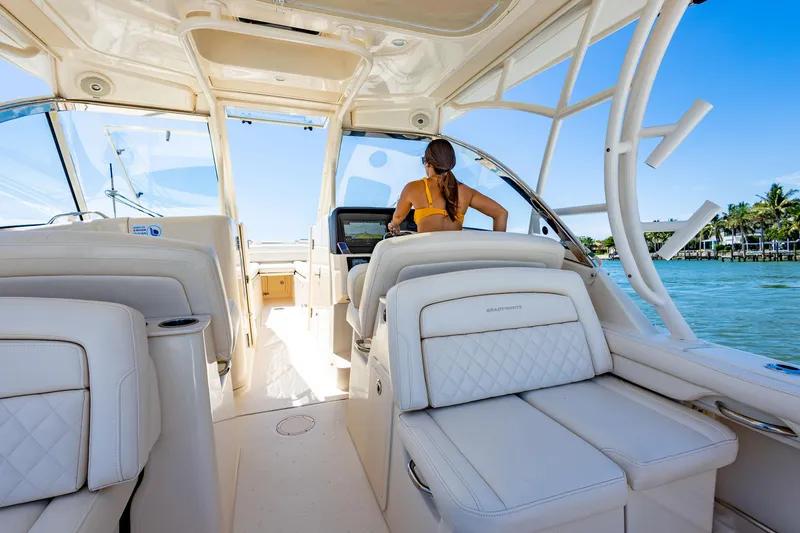  Yacht Photos Pics 2018 Grady-White Freedom 335 interior with woman at helm, cruising on clear waters.
