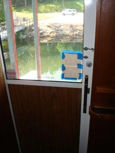  Yacht Photos Pics 1988 Chris-Craft Constellation boat door with taped window, overlooking water and dock.