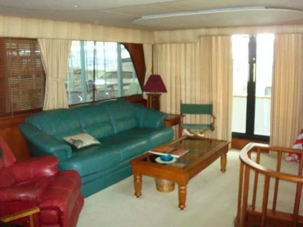 Yacht Photos Pics 1988 Chris-Craft Constellation yacht interior with green sofa, red chair, and wooden accents.