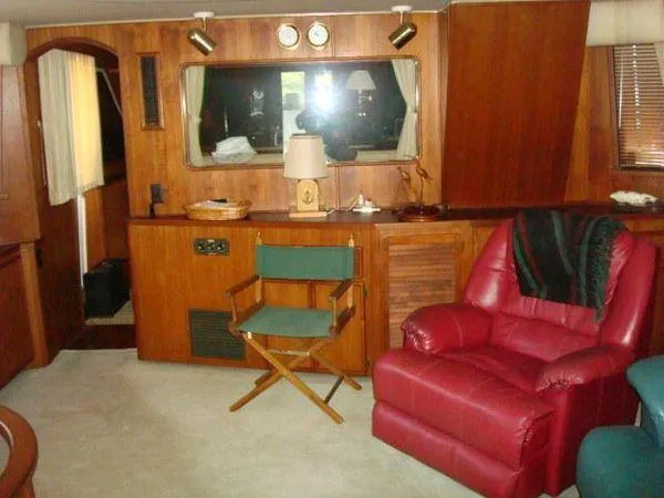  Yacht Photos Pics 1988 Chris-Craft Constellation interior with wood paneling, red recliner, and green director's chair.