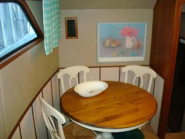  Yacht Photos Pics 1988 Chris-Craft Constellation interior with round wooden table and chairs, nautical decor.