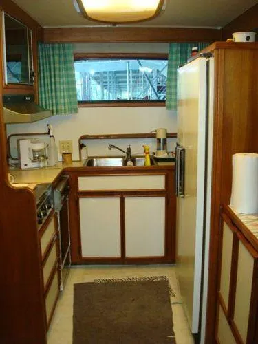  Yacht Photos Pics 1988 Chris-Craft Constellation kitchen with wooden cabinets, appliances, and a window view.