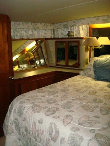  Yacht Photos Pics 1988 Chris-Craft Constellation bedroom with floral bedding, wooden cabinetry, and mirrored vanity.
