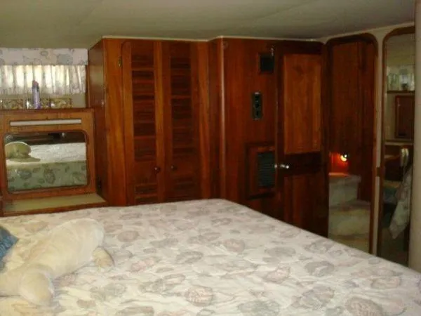  Yacht Photos Pics 1988 Chris-Craft Constellation cabin interior with wooden furnishings and a patterned bedspread.