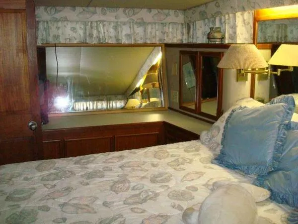  Yacht Photos Pics Cozy bedroom interior of 1988 Chris-Craft Constellation yacht with floral bedding and mirrored wall.