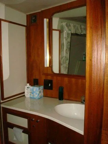  Yacht Photos Pics 1988 Chris-Craft Constellation bathroom with wooden cabinetry and a white countertop.