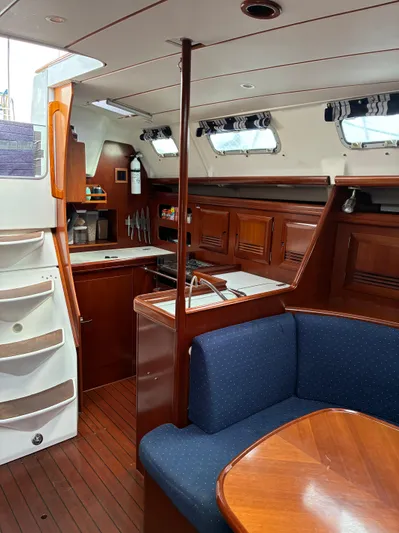 Danae Yacht Photos Pics Interior of 2003 Beneteau Oceanis Clipper 393 yacht with wooden cabinetry and blue seating.