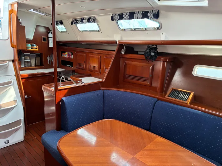 Danae Yacht Photos Pics Interior of 2003 Beneteau Oceanis Clipper 393 yacht with wooden furnishings and blue seating.