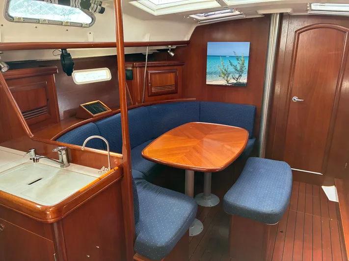 Danae Yacht Photos Pics Interior of 2003 Beneteau Oceanis Clipper 393 yacht with wooden dining area and blue seating.
