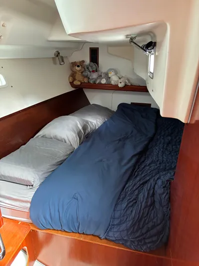 Danae Yacht Photos Pics Cozy cabin bed in 2003 Beneteau Oceanis Clipper 393 sailboat, with plush toys and navy bedding.