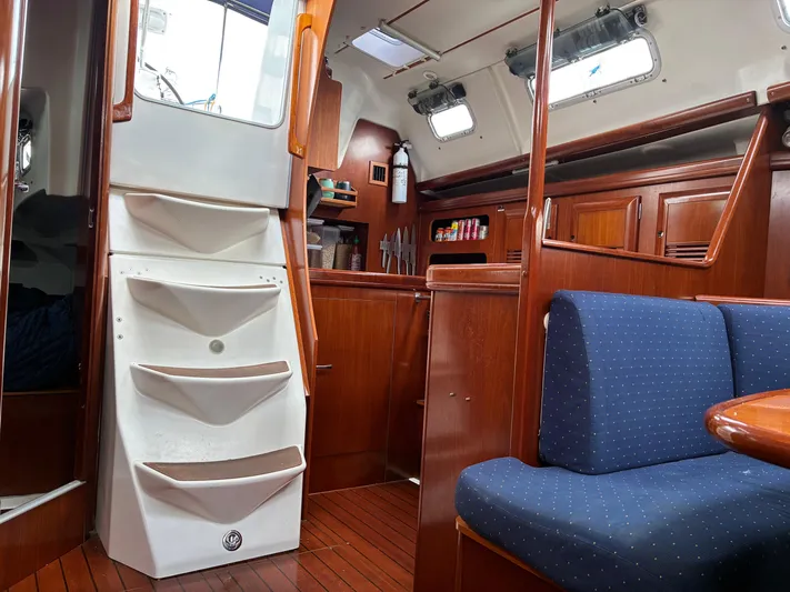 Danae Yacht Photos Pics Interior of 2003 Beneteau Oceanis Clipper 393 sailboat with wooden cabinetry and blue seating.