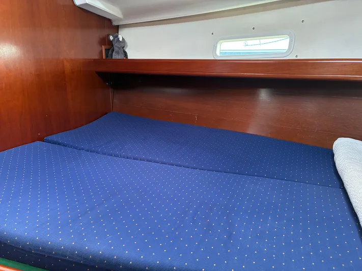 Danae Yacht Photos Pics Cozy cabin interior of 2003 Beneteau Oceanis Clipper 393 with blue bedding and wooden finish.